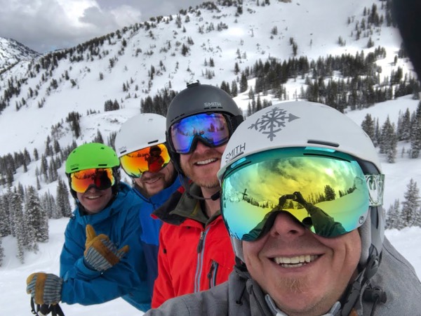4 people with skii helmets on smiling